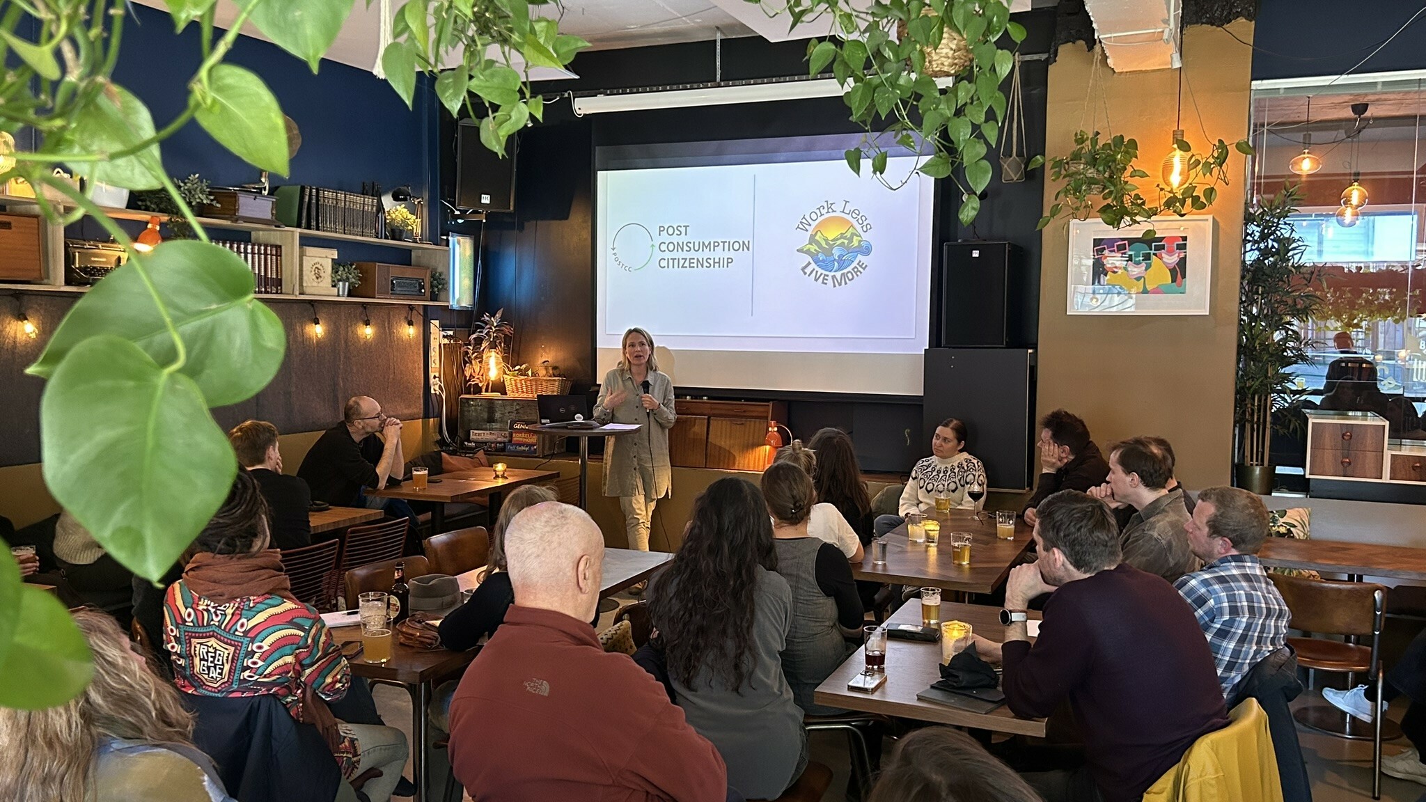 Fotografi av seminarlokale med mennesker som er vendt mot et lerret. Forsker Berit Nilsen presenterer Post Consumption Citizenship.