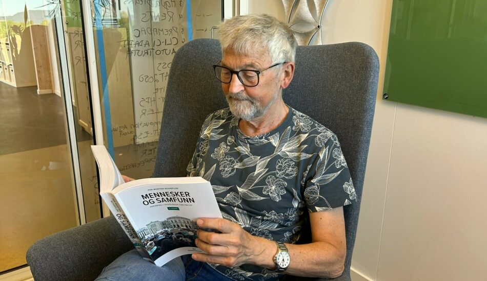Per Morten Schiefloe blar i sin nye bok "Mennesker og samfunn. Innføring i sosiologisk forståelse". Foto.