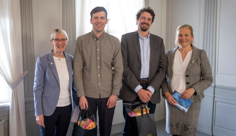 NTNU-rektor Anne Borg, førsteamanuensis Marius Korsnes, seniorforsker Mads Dahl Gjefsen og SINTEF-konsernsjef Alexandra Bech Gjørv står på rekke og smiler mot kamera. Korsnes og Gjefsen holder hver sin blomsterbukett. Foto.